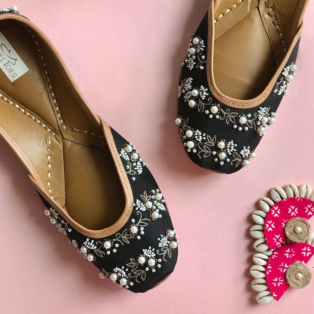 Handcrafted black juttis for women with zari embroidery and stylish pearl set embellishments.