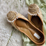 Gold colour handcrafted juttis for women with embellishments of beads, zari, pearls and katdana.
