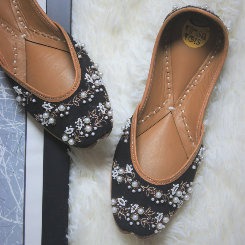 Handcrafted black juttis for women with zari embroidery and stylish pearl set embellishments.